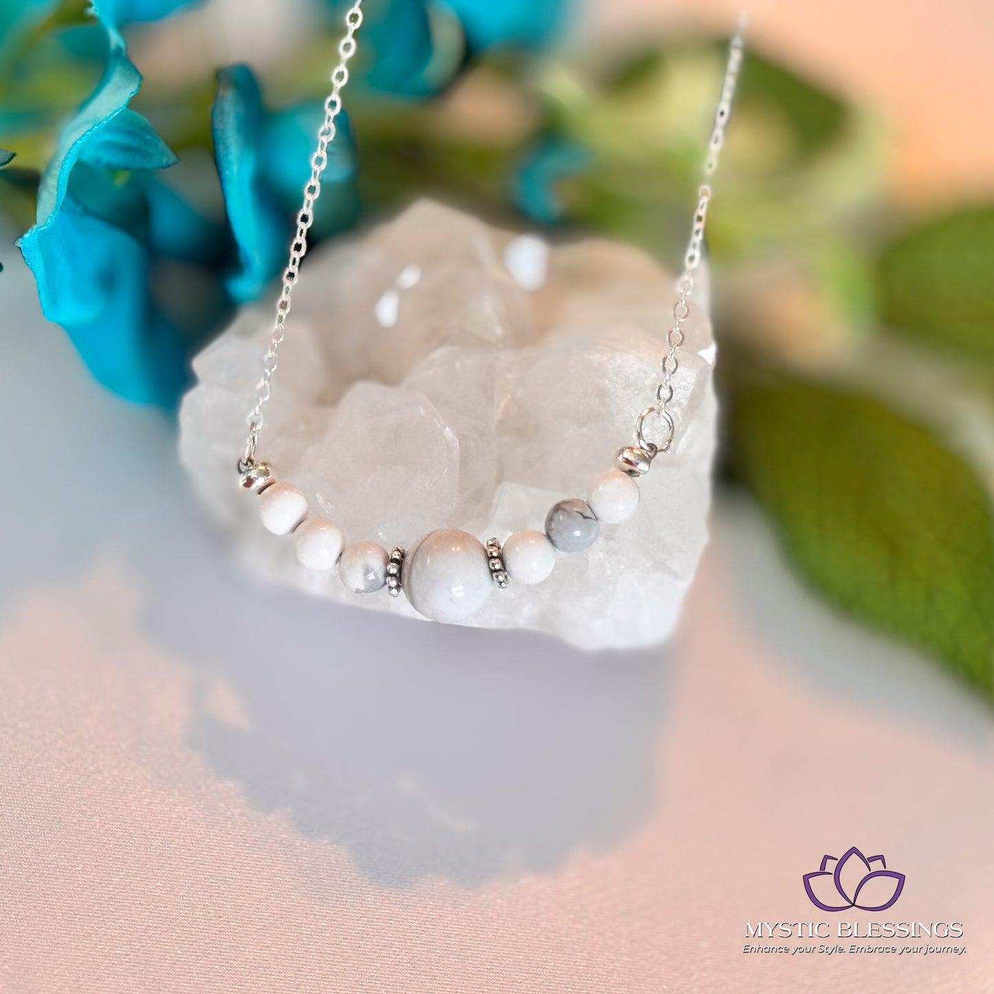 a white necklace with pearls on it sitting on top of a rock