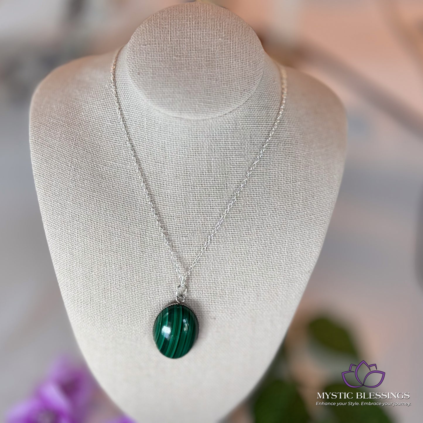 a white mannequin with a green necklace on it