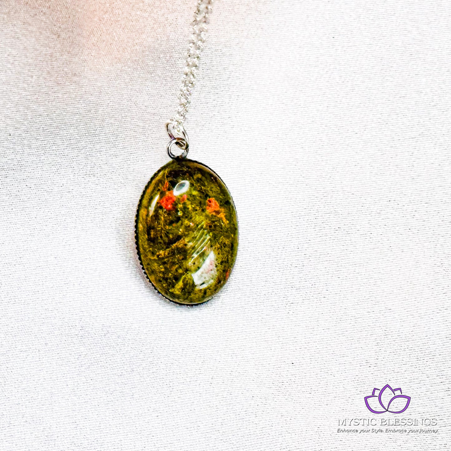 a necklace with a green pendant hanging from a silver chain