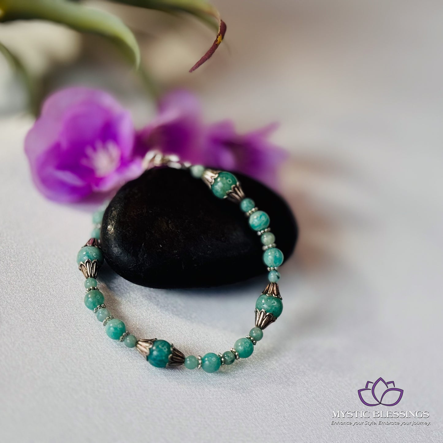 a green beaded bracelet sitting on top of a rock
