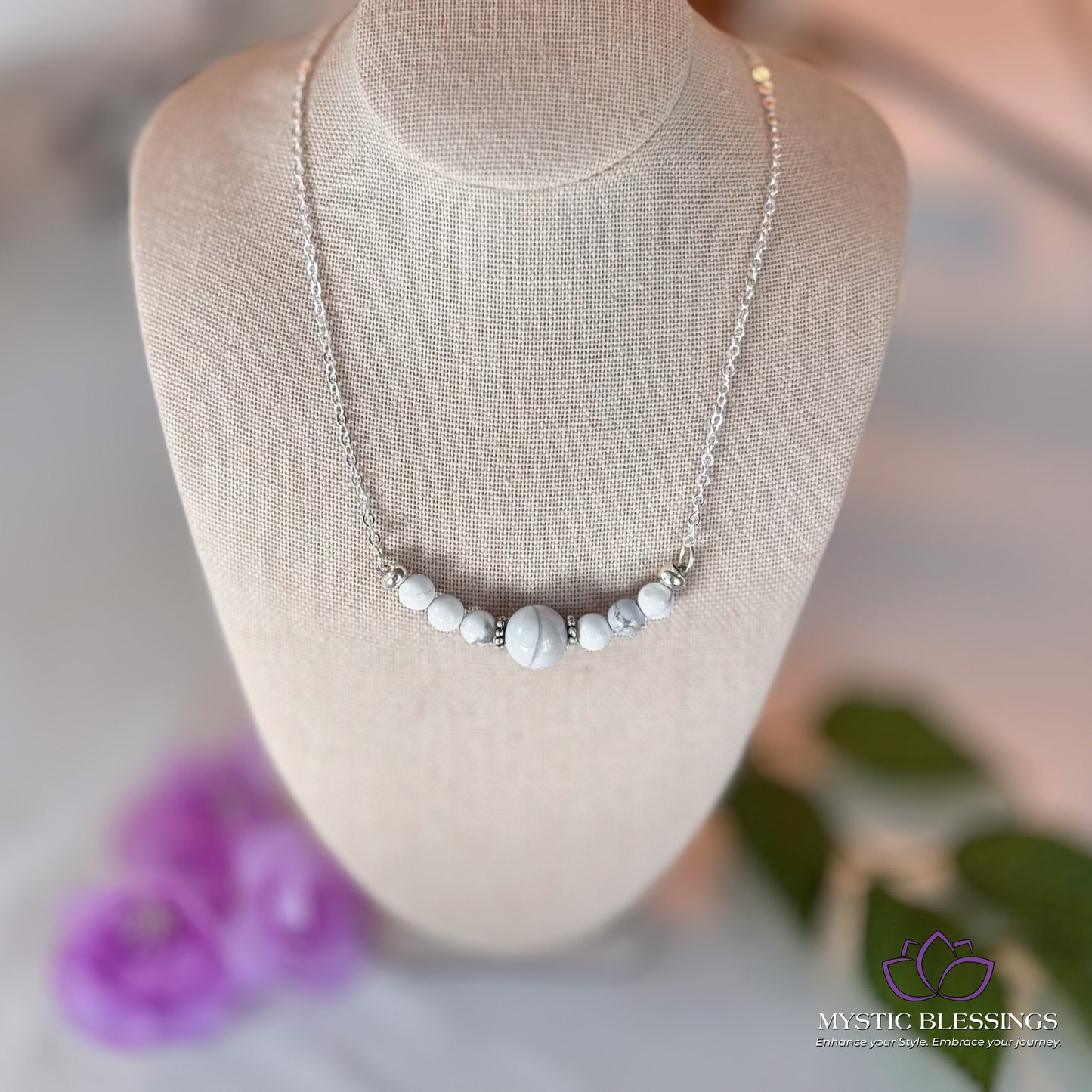a white necklace on a mannequin with flowers in the background