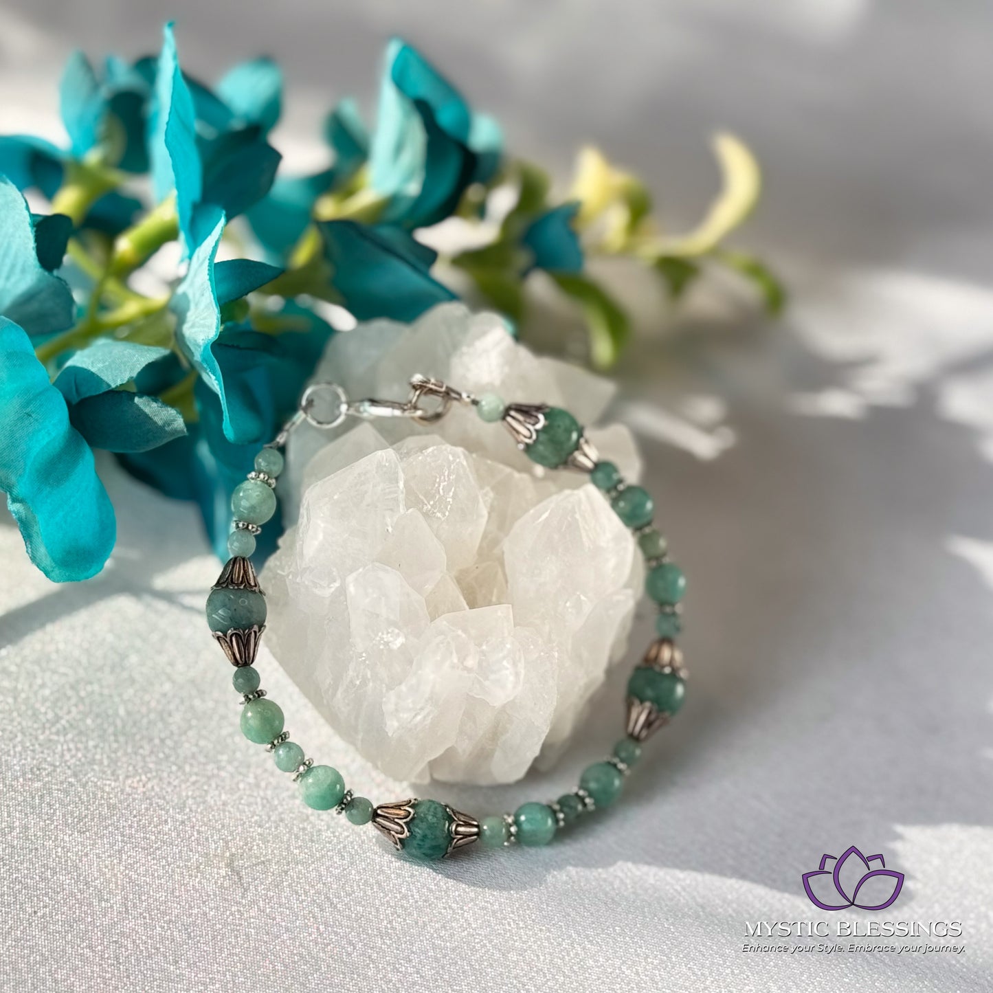 a bracelet with beads and a flower on a table