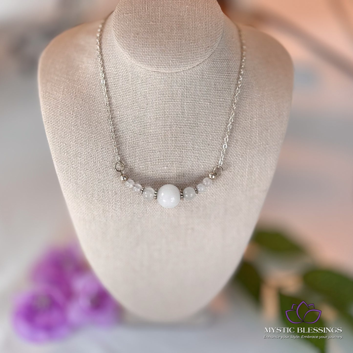a white necklace on a mannequin with flowers in the background