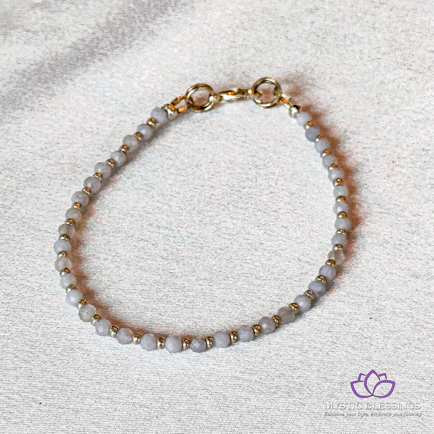 a white beaded bracelet with a gold clasp
