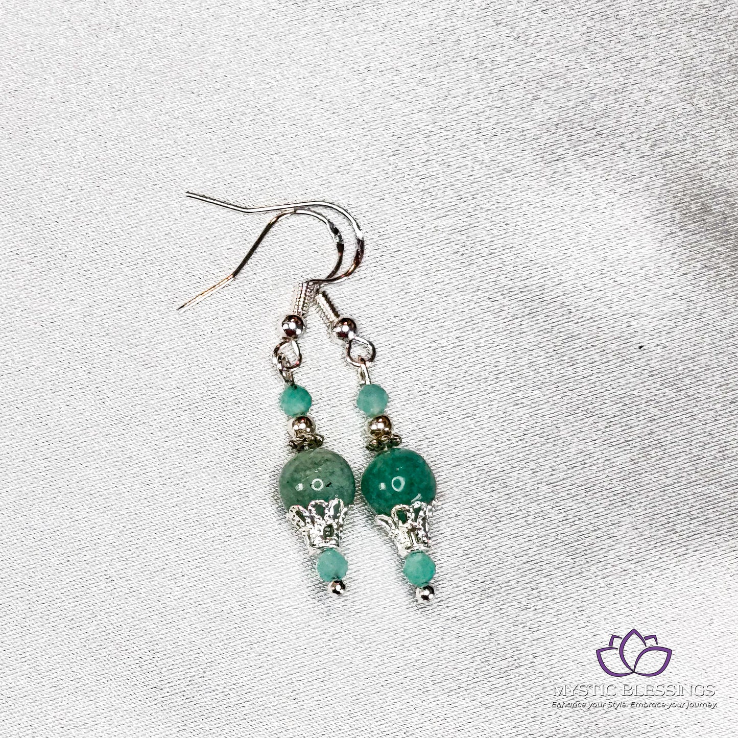a pair of earrings with green beads and silver beads