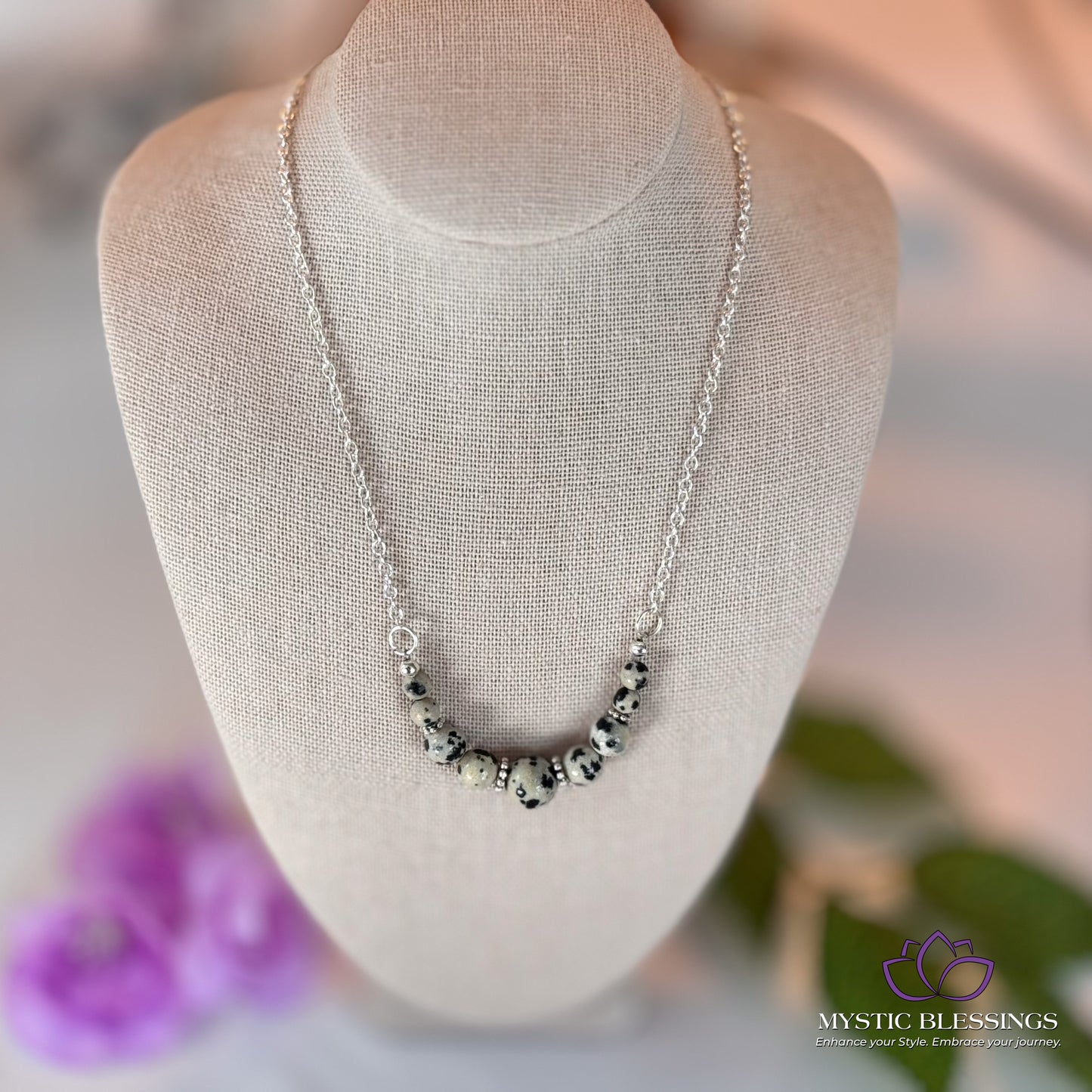 a necklace on a mannequin with flowers in the background