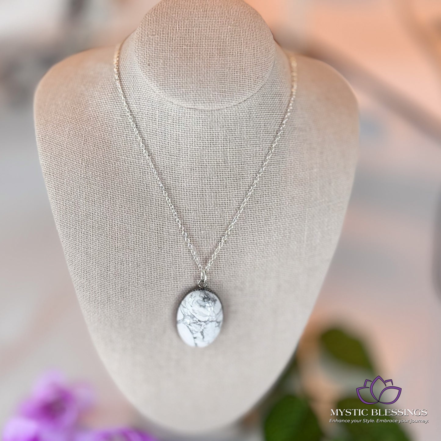 a necklace on a mannequin with flowers in the background