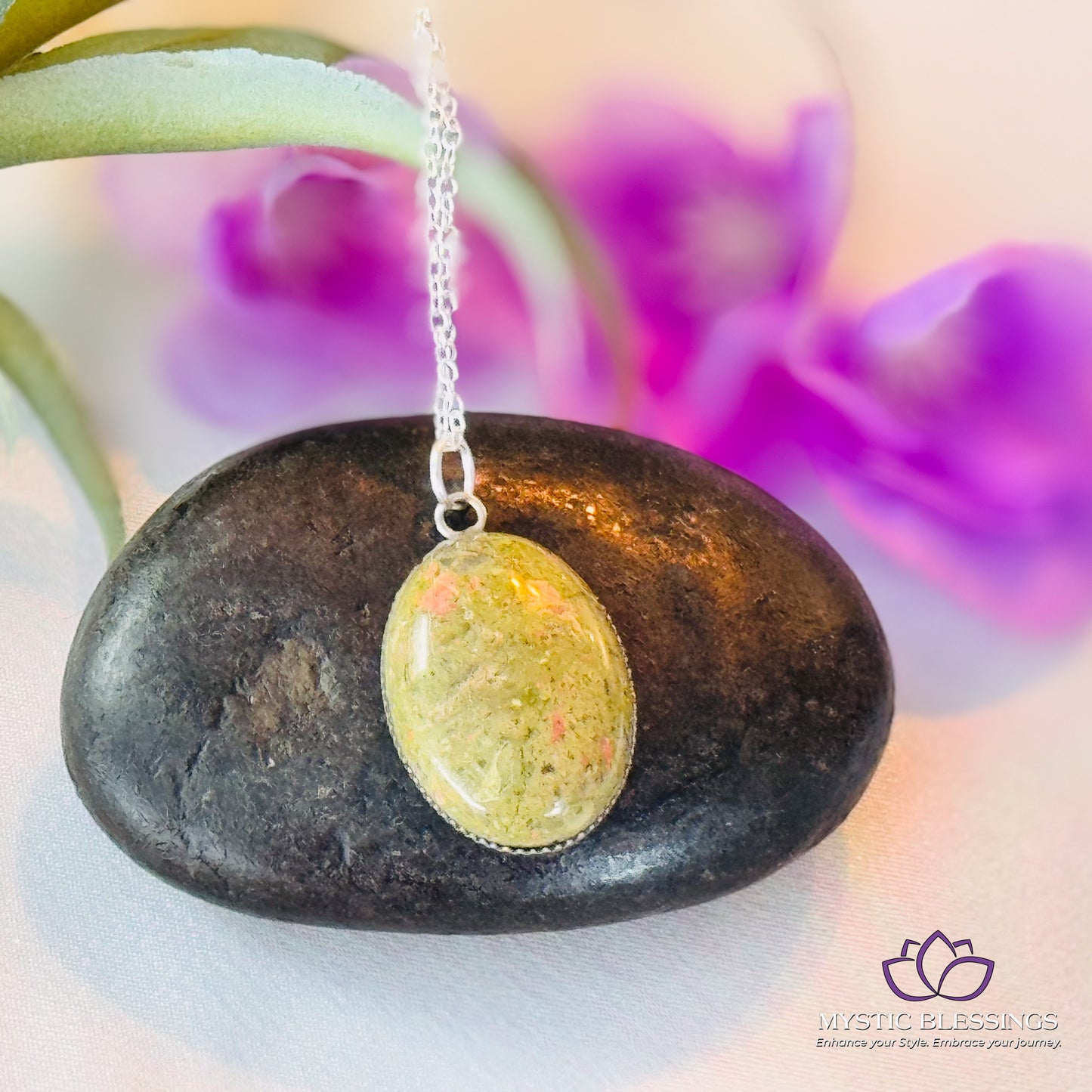 a rock with a pendant on it sitting next to a flower
