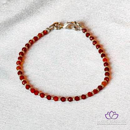 a red beaded bracelet on a white surface