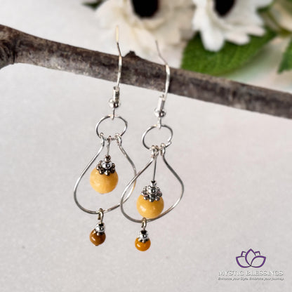 a pair of silver and yellow earrings on a branch