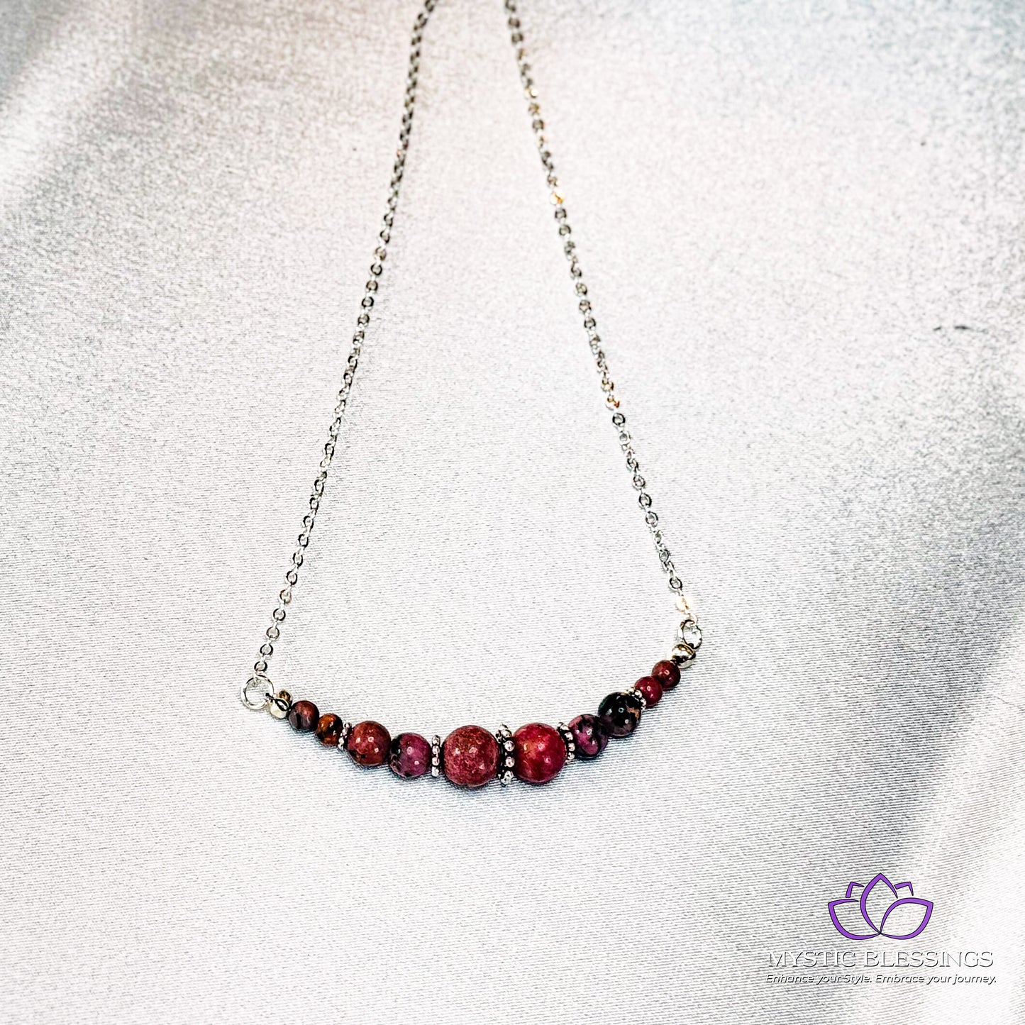 a silver chain with a red bead on it