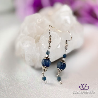 a pair of blue beaded earrings sitting on top of a rock