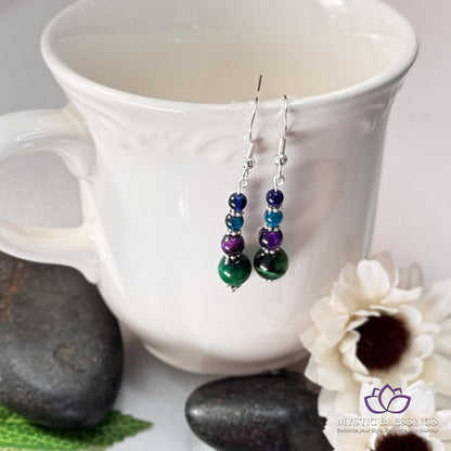 a pair of earrings sitting on top of a white cup