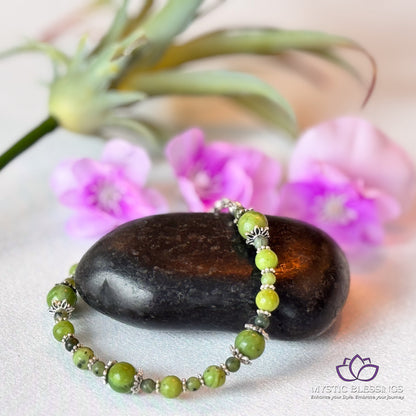 a green beaded bracelet sitting on top of a rock