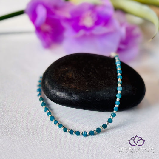 a blue beaded necklace sitting on top of a rock