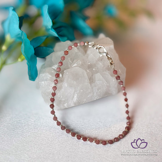 a pink beaded necklace sitting on top of a rock