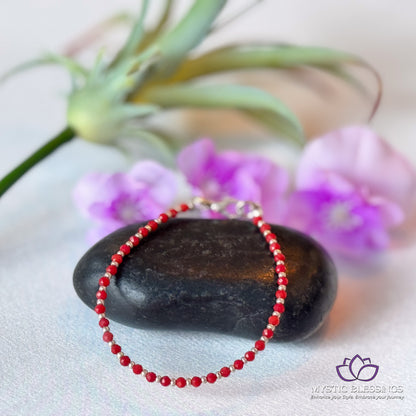 a red beaded bracelet sitting on top of a rock