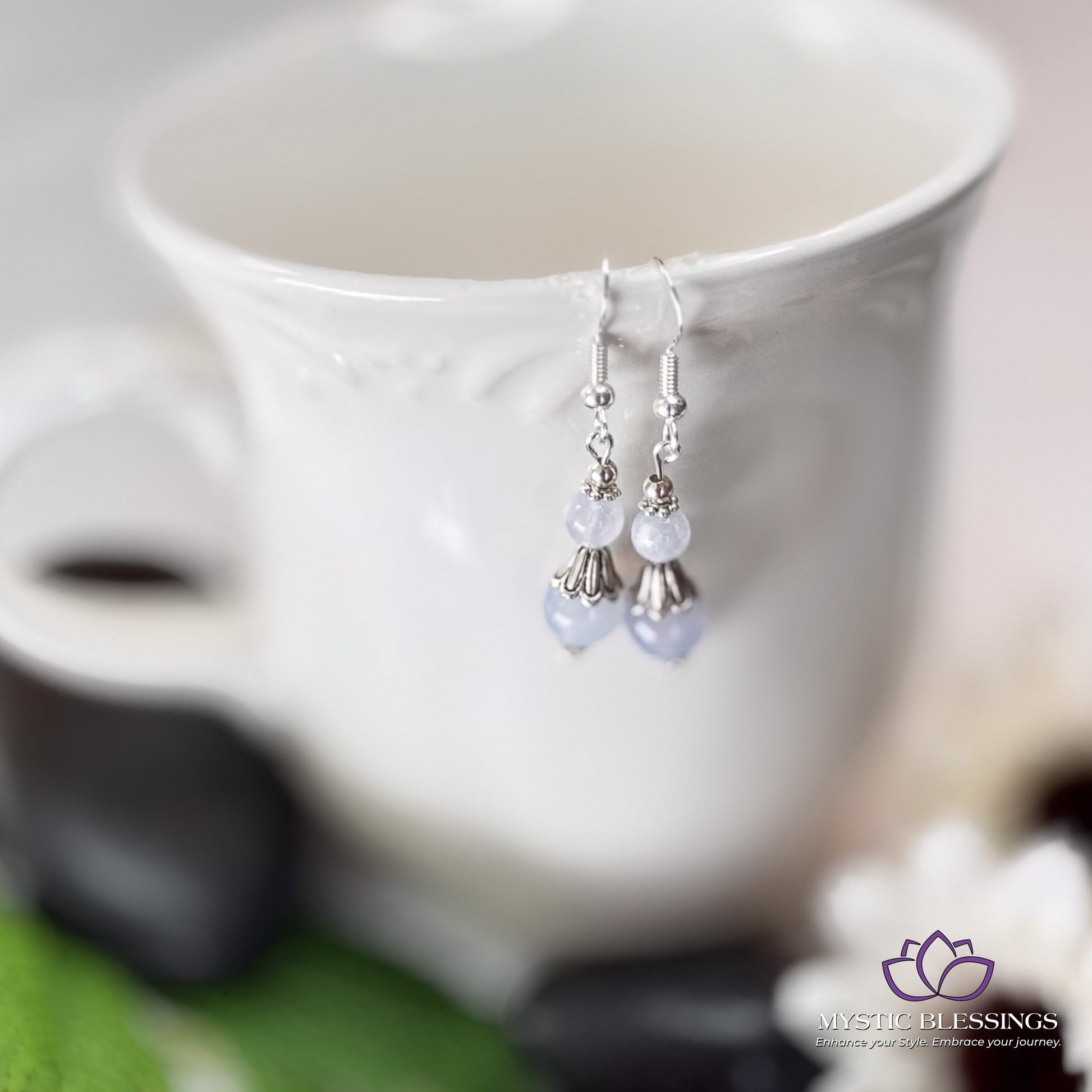 a cup with a pair of earrings hanging from it