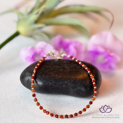 a red beaded bracelet sitting on top of a rock