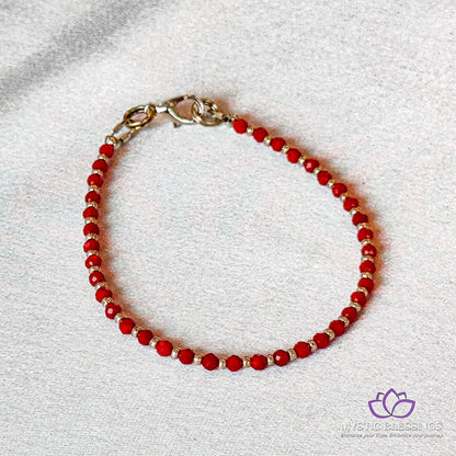 a red beaded bracelet on a white surface