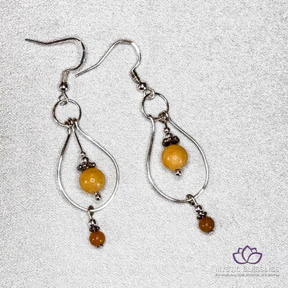 a pair of silver earrings with yellow beads