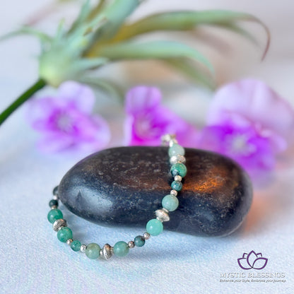 a green beaded bracelet sitting on top of a rock