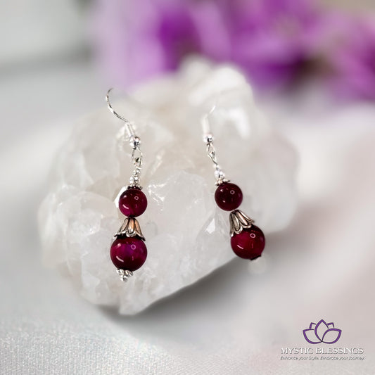 a pair of red glass beaded earrings sitting on top of a rock