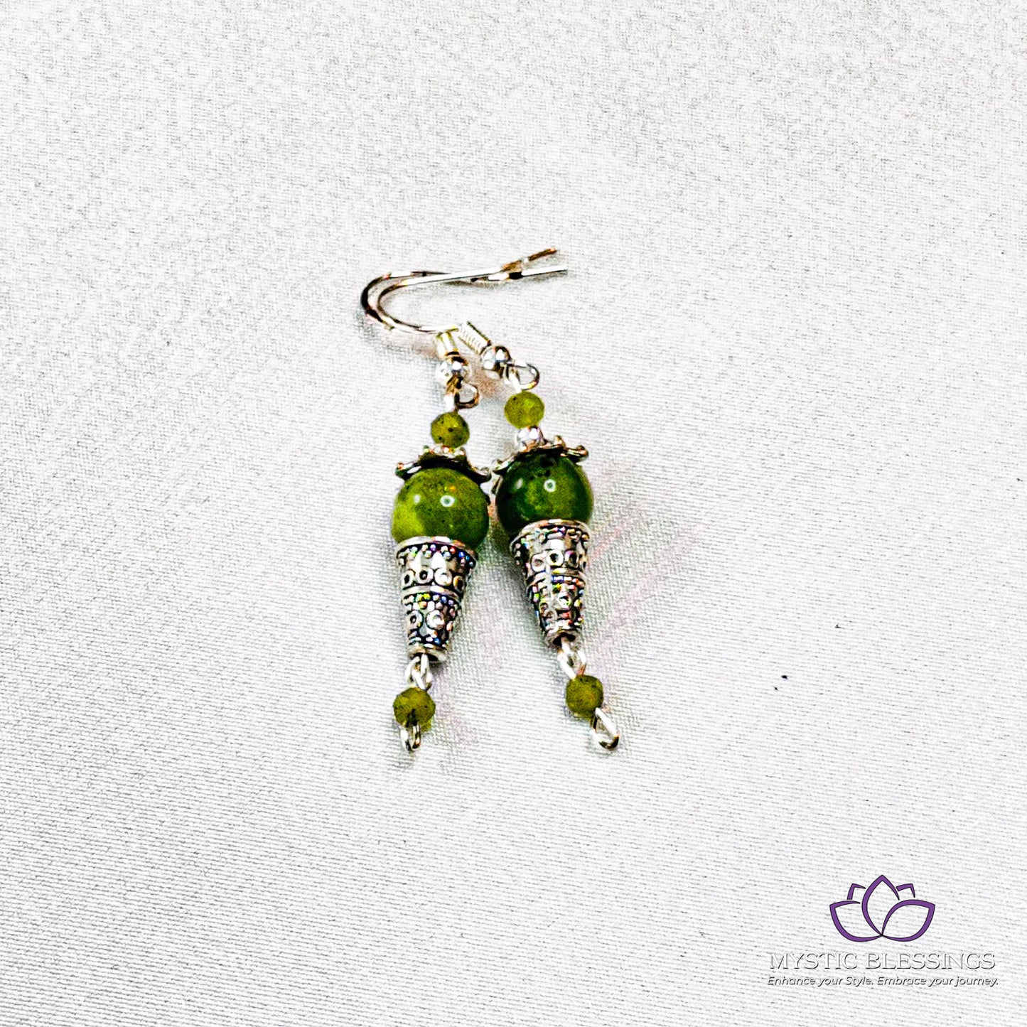 a pair of earrings with green beads on them