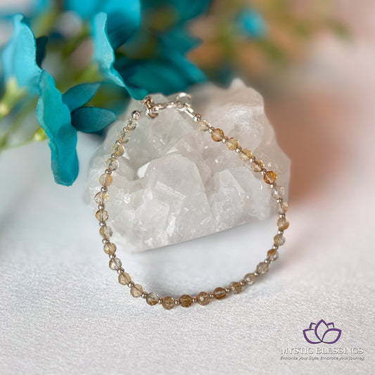 a bracelet sitting on top of a rock next to flowers