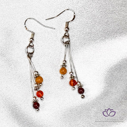 a pair of silver earrings with red, orange and yellow beads